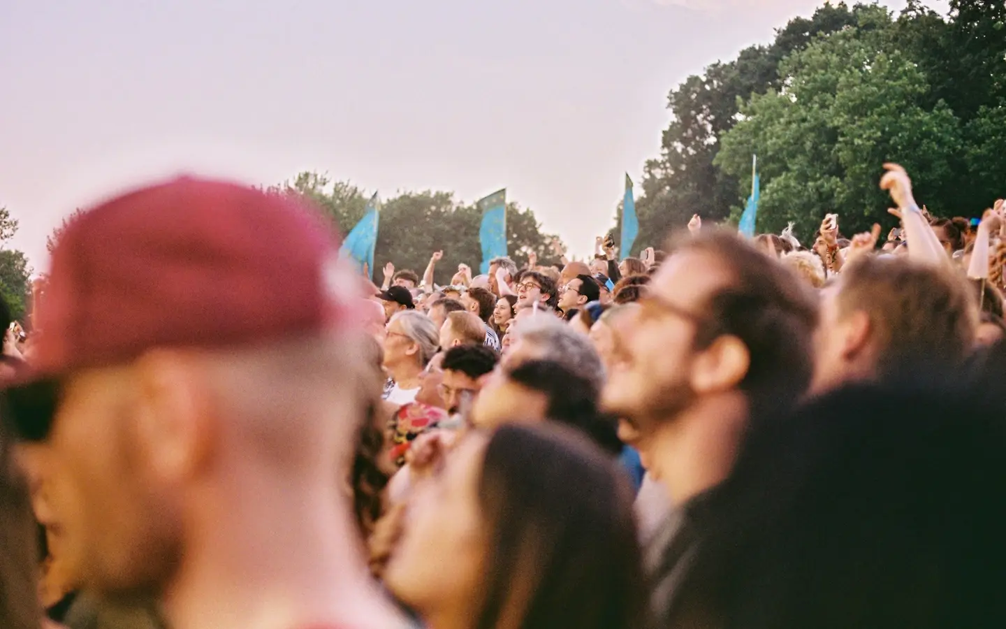Festival crowd photographed at golden hour beneath hanging flags