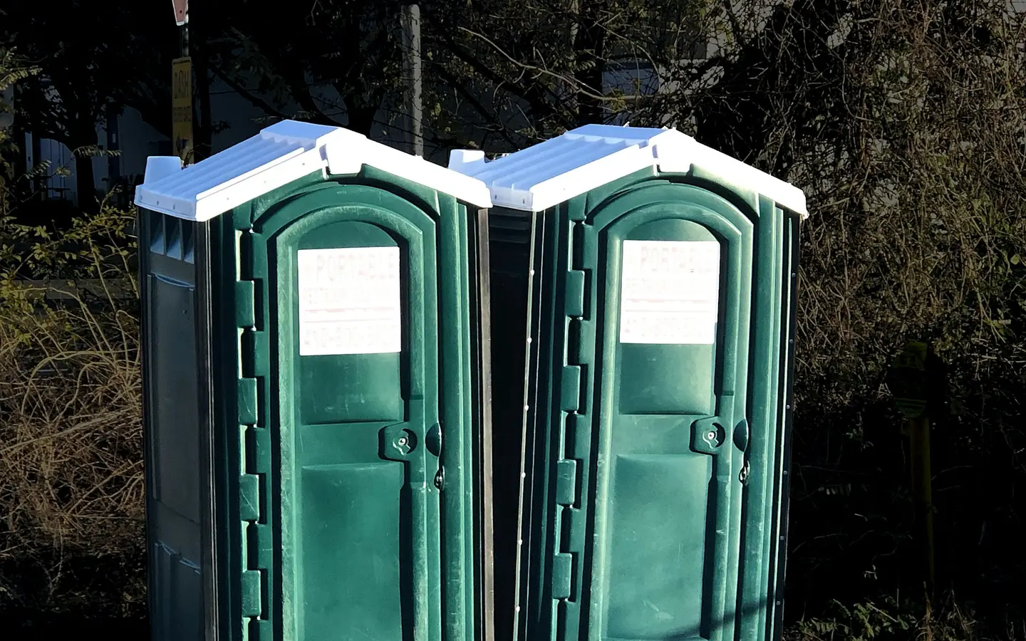 A pair of portable toilets positioned side by side at an outdoor site